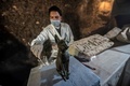 エジプトの古代都市サッカラの発掘現場で新たに発見された猫の銅像をクリーニングする考古学者（2018年11月10日撮影）。(c)KHALED DESOUKI / AFP