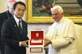 8日からイタリア・ラクイラ（L&apos;Aquila）で開催される主要8か国（G8）首脳会議参加のため同国入りした麻生太郎（Taro Aso）首相は7日、バチカン市国を訪問し、ローマ法王ベネディクト16世（Benedict XVI）と会談した。写真は、内謁中、法王（右）から贈り物を受ける麻生首相（2009年7月7日撮影）。(c)AFP/DANILO SCHIAVELLA
