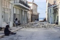 ギリシャのサモス島で、地震により損壊した建物のそばを歩く人々（2020年10月30日撮影）。(c)STR / Eurokinissi / AFP