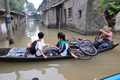 洪水により家屋が浸水した中国・浙江省（Zhejiang）杭州（Hangzhou）で、ボートに自転車を積んで帰宅する児童（2008年6月18日撮影）。(c)AFP