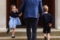 父親のウィリアム英王子に連れられて、母親のキャサリン妃と生まれたばかりの弟が入院するロンドンにあるセント・メアリー病院の特別病棟「リンド・ウイング」を訪れた際、振り返って報道陣に手を振るシャーロット王女（左）。右は兄のジョージ王子（2018年4月23日撮影）。(c)AFP PHOTO / Ben STANSALL