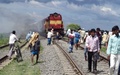 インド東部ビハール（Bihar）州カガリア（Khagaria）で巡礼者に突っ込む事故を起こした鉄道の客車。感情的になった群集により火を放たれ煙が上がっている（2013年8月19日撮影）。(c)AFP