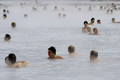 写真はアイスランドの首都レイキャビク（Reykjavik）郊外にある温泉｢ブルーラグーン（Blue Lagoon）｣を楽しむ観光客。ブルーラグーンは水の色が青と緑であることから、この名で呼ばれている。健康効果もうたわれている（2009年4月26日撮影）。(c)AFP/OLIVIER MORIN