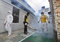 韓国の宗教団体「新天地イエス教会」の大邱支部付近の住宅街で消毒を行う作業員ら（2020年2月27日撮影）。(c)Jung Yeon-je / AFP