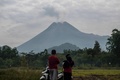 インドネシア・ジョクジャカルタで、ムラピ山から煙が立ち上る様子を見る住民ら（2021年1月25日撮影）。(c)Agung Supriyanto / AFP