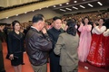 北朝鮮・平壌（Pyongyang）で開催された「牡丹峰楽団（Moranbong Band）」の公演で、朝鮮人民軍の飛行士の家族に声をかける金正恩（キム・ジョンウン、Kim Jong-Un）第1書記（中央）と、李雪主（リ・ソルジュ、Ri Sol-Ju）夫人（左端、2014年4月16日撮影、同20日配信）。(c)AFP/KCNA via KNS