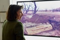ニューヨーク（New York）のハート島（Hart Island）でジョエル・スターンフェルド（Joel Sternfeld）さんが撮影した、幼児のためのひつぎの写真と前に立つ「ハート島プロジェクト（Hart Island Project）」のメリンダ・ハント（Melinda Hunt）さん。（2014年4月2日撮影）。(c)AFP/Stan HONDA 