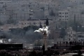 シリア北部アインアルアラブ（Ain al-Arab、クルド名：コバニ、Kobane）中心部のモスクの塔から立ち上る砲撃の煙。国境の反対側トルコ・シャンルウルファ（Sanliurfa）県の村ムルシトピナル（Mursitpinar）より（2014年10月13日撮影）。(c)AFP/ARIS MESSINIS