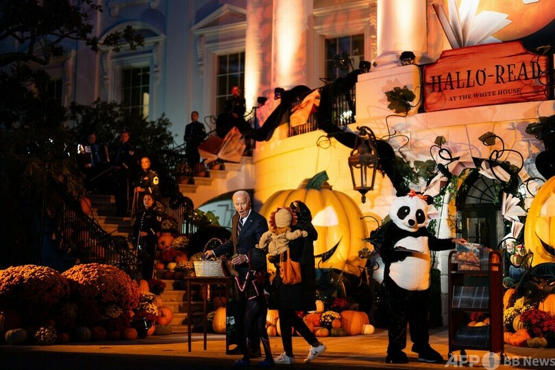 米首都ワシントンのホワイトハウスで行われたハロウィーンのイベントで、子どもにお菓子を渡すジョー・バイデン大統領と着ぐるみ姿の妻のジル氏（2024年12月30日撮影）。(c)Tierney CROSS / AFP