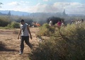 南米アルゼンチン北西部ラリオハ州のビージャカステリ近郊で、空中衝突して墜落・炎上したヘリコプターの残骸の周りを歩く人々（2015年3月9日撮影）。(c)AFP/ALDO PORTUGAL