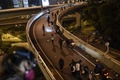 香港理工大学の構内から脱出するため、歩道橋から幹線道路へとロープで下りて走るデモ参加者（2019年11月18日撮影）。(c)AFP/Ye Aung Thu