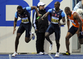 第12回世界陸上ベルリン大会（%%12th IAAF World Championships in Athletics Berlin%%）男子4×100メートル予選。日本は38秒53を記録し、トリニダード・トバゴに次ぐ1組2位で5大会連続の決勝進出を決めた。

　前回優勝の米国は2組1位だったが、第3走のショーン・クロフォード（%%Shawn Crawford%%）からダービス・パットン（%%Darvis Patton%%）へのバトン受け渡しが規定の範囲を越えていたため、失格処分となった。写真はチームメイトのダービス・パットン（左）にバトンを渡す米国のショーン・クロフォード（右2）。（2009年8月21日撮影）(c)AFP/OLIVIER MORIN