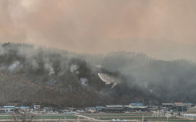 韓国南東部の義城郡で発生した山火事の消火に当たるヘリコプター（2025年3月22日撮影）。（c）YONHAP/AFP