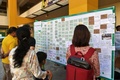 シンガポールの小学校で、マレーシア・ボルネオ島で発生した地震で犠牲となった児童らに寄せられた追悼メッセージを読む人々（2015年6月7日撮影）。(c)AFP/ROSLAN RAHMAN