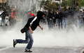 ギリシャ・アテネ（Athens）の郊外Koyrdallosにある同国最大の刑務所前で、催涙ガスから逃げる若者ら（2008年12月11日撮影）。(c)AFP/Louisa Gouliamaki