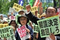 都内・国会議事堂そばで行われた安倍政権への抗議デモで、プラカードを掲げスローガンを唱えるデモ参加者（2014年7月14日撮影）。(c)AFP/Yoshikazu TSUNO