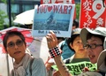 都内・国会議事堂そばで行われた安倍政権への抗議デモで、プラカードを掲げスローガンを唱えるデモ参加者（2014年7月14日撮影）。(c)AFP/Yoshikazu TSUNO