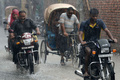 インドのアムリトサル（Amritsar）で、豪雨の中をバイクで移動する人たち（2013年8月12日撮影）。(c)AFP/NARINDER NANU