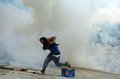 イスラエル・ヨルダン川西岸（West Bank）のヘブロン（Hebron）で、イスラエル軍が発砲した催涙弾から逃げるパレスチナ人の若者（2011年5月15日撮影）。(c)AFP/HAZEM BADER