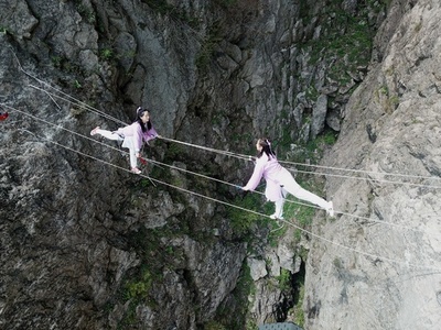 まるで岩場の曲芸師 女性ガイド、古代装束で絶壁登る