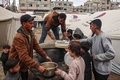 パレスチナ自治区ガザ南部ラファで、配給のスープを避難民に手渡すボランティア（2024年2月18日撮影）。(c)SAID KHATIB / AFP
