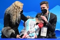 北京冬季五輪、フィギュアスケート女子シングル・フリースケーティング（FS）。キスアンドクライで涙するロシア五輪委員会（ROC）のカミラ・ワリエワ（中央）を慰めるコーチのエテリ・トゥトベリーゼ氏（左、2022年2月17日撮影）。(c)Manan VATSYAYANA / AFP 