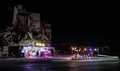 シリアの反体制派が支配する北西部イドリブ県アリハで、内戦で激しく損壊した建物の1階部分に設けられたカフェと、その前を通り過ぎる車を捉えた長時間露光写真（2021年7月11日撮影）。(c)AAREF WATAD / AFP