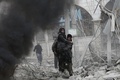 シリア政府軍とロシア軍によるものとされる爆撃があったシリア首都ダマスカス近郊の東グータで、負傷した女性を抱えて歩く男性（2018年1月6日撮影）。(c)AFP PHOTO / ABDULMONAM EASSA