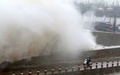 台風21号による波が打ち付ける中国・福建省泉州の防波堤の横を走る2人乗りのスクーター（2015年9月29日撮影）。(c)AFP