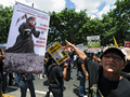 南米ベネズエラの首都カラカス（Caracas）で20日、街中での治安改善を求める抗議行動が行われた。写真は、ウゴ・チャベス（Hugo Chavez）大統領を描いたプラカードを指さす女性（2009年6月20日撮影）。(c)AFP/Juan Barreto