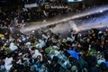 トルコ・イスタンブールにある大手日刊紙ザマン本社前で警察の機動隊から放水銃の水と催涙ガスを浴びせられるデモ参加者ら（2016年3月4日撮影）。(c)AFP/OZAN KOSE