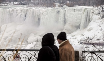 凍り付いたナイアガラの滝に集まる観光客ら