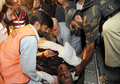 パキスタン・ペシャワル（Peshawar）の5つ星ホテル「パールコンチネンタルホテル」（Pearl Continental hotel）での爆発で負傷した男性を運ぶボランティア（2009年6月10日撮影）。(c)AFP/Tariq MAHMOOD
