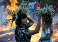 伝統的なスラブ民族の祭り「イワン・クパーラ（Ivan Kupala）の夜」が6日、東欧各地で行われた。起源をキリスト教以前にまでさかのぼるというこの祭りでは、人々が花輪を編んだり、たき火を飛び越えたり、裸で泳いだりして祝う。

写真はベラルーシ南部トゥーロフ（Turov）で、たき火の脇で花輪をかぶった女性と少女（2013年7月6日撮影）。(c)AFP/VIKTOR DRACHEV