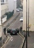仏パリ（Paris）にある風刺週刊紙シャルリー・エブド（Charlie Hebdo）の本社付近で警察官と対峙する武装した2人の男（2015年1月7日撮影）。(c)AFP/ANNE GELBARD