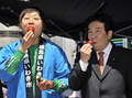 都内即売会で福島県いわき市産のイチゴを食べる枝野幸男（Yukio Edano）官房長官（右）と、トマトを食べるお笑いコンビ南海キャンディーズのしずちゃんこと山崎静代（Shizuyo Yamasaki）さん（左、2011年4月12日撮影）。(c)AFP/Yoshikazu TSUNO