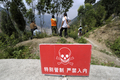 中国・四川大地震により四川（Sichuan）省北川（Beichuan）県の唐家山（Tangjiashan）にできた巨大な「せき止め湖」を眺める人々と危険と立ち入り禁止を警告する標識（2008年6月10日撮影）。(c)AFP/LIU Jin