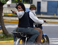 2007年11月7日、ベネズエラの首都カラカス（Caracas）で、大学のキャンパスにバイクで乗りつけ、大統領権限強化を認める改憲案反対デモに参加した学生たちに発砲する2人組。(c)AFP/Pedro REY