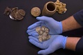 ユダヤ砂漠にあるムラバアト洞窟の発掘現場で見つかった15枚の銀貨。出土した筒（上）の中に入っていた（2022年12月13日撮影）。(c)MENAHEM KAHANA / AFP