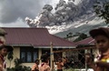 インドネシアのカロで、火山灰を噴き上げるシナブン山を背にして、校舎の外で遊ぶ小学生たち（2017年2月10日撮影）。(c)AFP