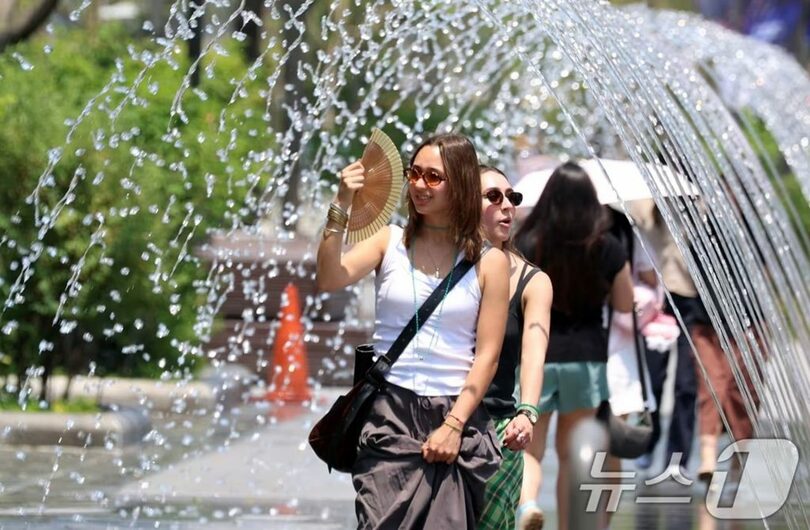 17日、ソウル市鍾路区の光化門広場の噴水で、外国人観光客が水遊びをしながら暑さをしのいでいる(c)news1
