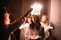 英イングランド北部ヨークで行われた伝統行事「聖ルチア祭」で、頭上に載せた冠のろうそくに火をともされるルチア役の女性（2021年12月3日撮影）。(c)Oli SCARFF / AFP