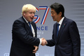 ボリス・ジョンソン英首相（左）と握手を交わす安倍晋三元首相（2019年8月26日撮影）。(c)NEIL HALL / POOL / AFP