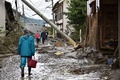 台風19号（アジア名：ハギビス）の影響を受けた長野県で、洪水の被害に見舞われた住宅の脇を歩く住民ら（2019年10月15日撮影）。(c)Kazuhiro NOGI / AFP