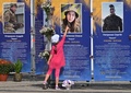 屋外に展示されたウクライナの軍事組織「アゾフ旅団」の戦没者の写真を指差す女の子。ウクライナ・キーウで（2024年9月23日撮影）。(c)Sergei SUPINSKY / AFP