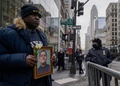 ウィルバート・モラ巡査の写真を持つ男性。米ニューヨークで（2022年2月2日撮影）。(c)Ed JONES / AFP