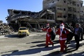 シリア北部ラッカで、破壊された建物の横を通り過ぎるサンタクロースの格好をした男性ら（2017年12月26日撮影）。(c)AFP PHOTO / Delil souleiman