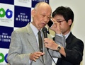 ノーベル医学生理学賞の受賞が決まったことを受けて東京都内の北里大学で開かれた記者会見中に安倍晋三首相からの電話を受ける大村智・北里大特別栄誉教授（左、2015年10月5日撮影）。(c)AFP/Yoshikazu TSUNO