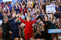 米ノースカロライナ州ローリーのノースカロライナ州立大学で行われた米大統領選の民主党候補ヒラリー・クリントン氏（中央）の選挙集会で、クリントン氏をステージ上に上げるレディー・ガガさん（右）とジョン・ボン・ジョヴィさん（左、2016年11月7日撮影）。(c)AFP/Logan Cyrus