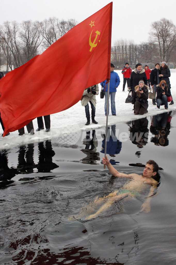 凍てつく気温もへっちゃら、旧ソ連国旗を手に泳ぐ男性 ロシア 写真1枚 国際ニュース：AFPBB News